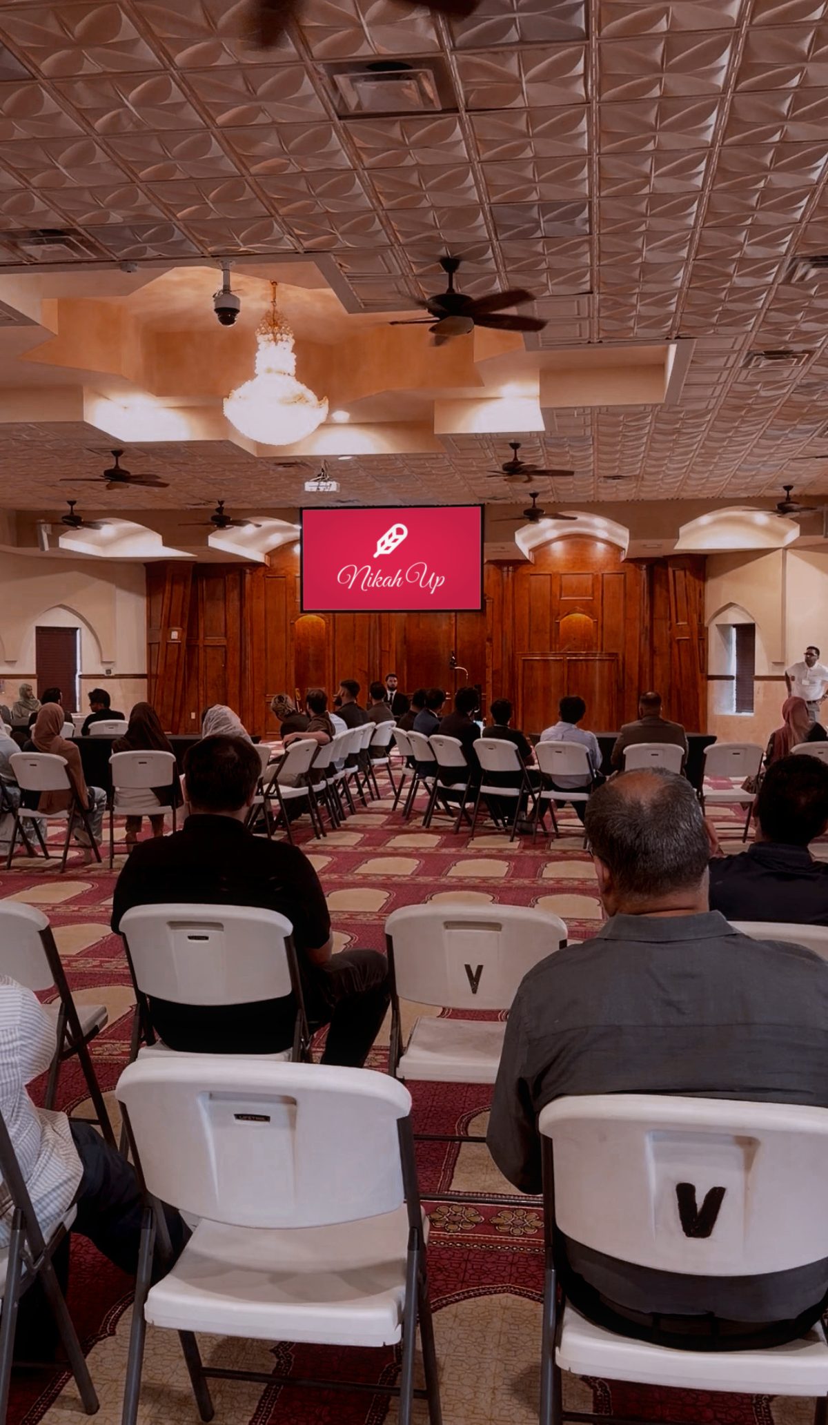 The men’s seating under the chandelier, looking toward the front of the hall.